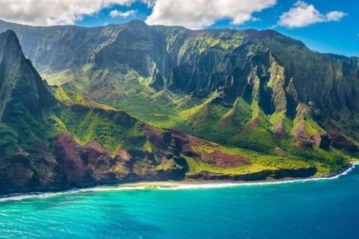 an island with water and Nā Pali Coast State Park in the background